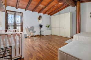 Une chambre avec un plafond en bois, une armoire blanche, un lit et un radiateur.