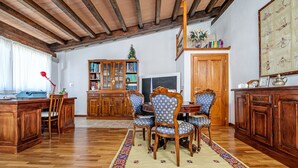 A wooden dining area with a table and chairs, a bookshelf, and a television. - Triple Room with Mountain View, Shared Terrace and Wi-Fi (Telti)