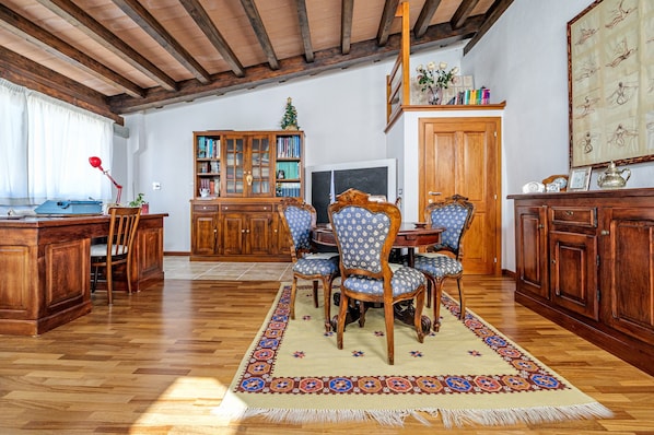 Un coin repas en bois avec une table et des chaises, une bibliothèque et un téléviseur.