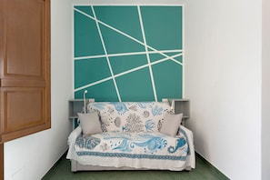 Een slaapkamer met een bed, een muur in een blauwgroene tint en een houten deur.