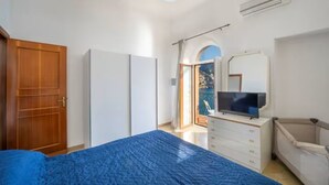 Une chambre à coucher avec un lit, une commode, un téléviseur et une fenêtre.