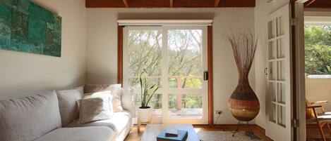 A modern living room with a sofa, a coffee table, a large vase, and a sliding glass door leading to an outdoor area.