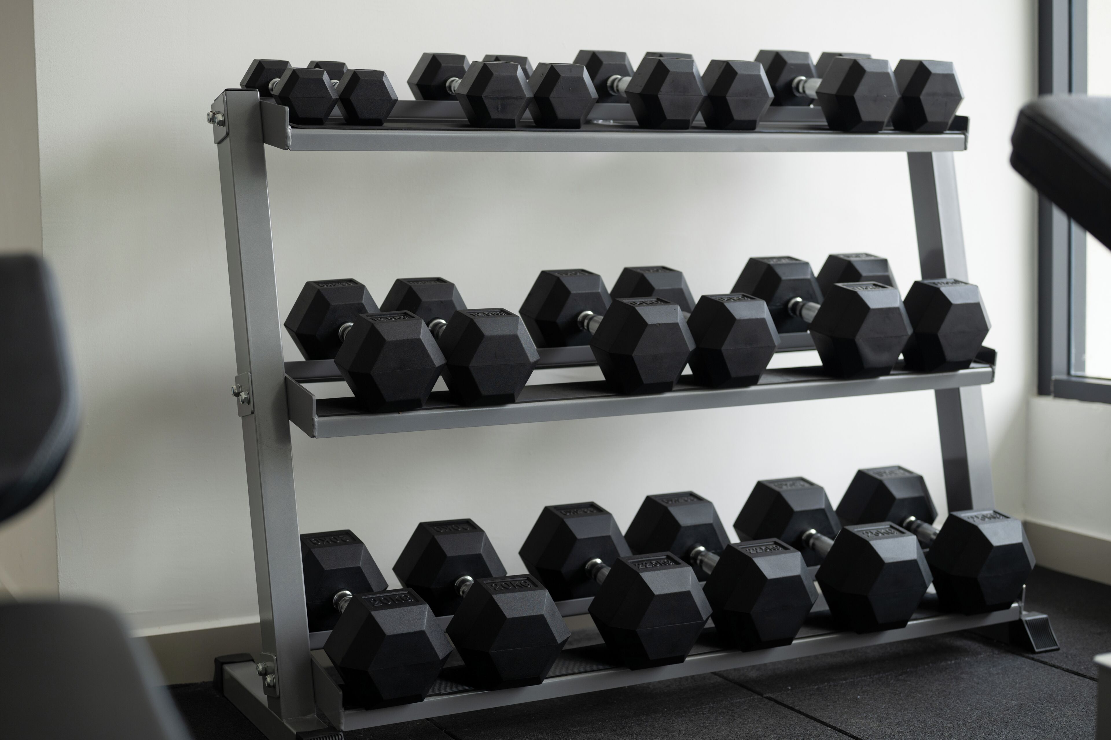 A rack of hexagonal dumbbells in a gym setting.