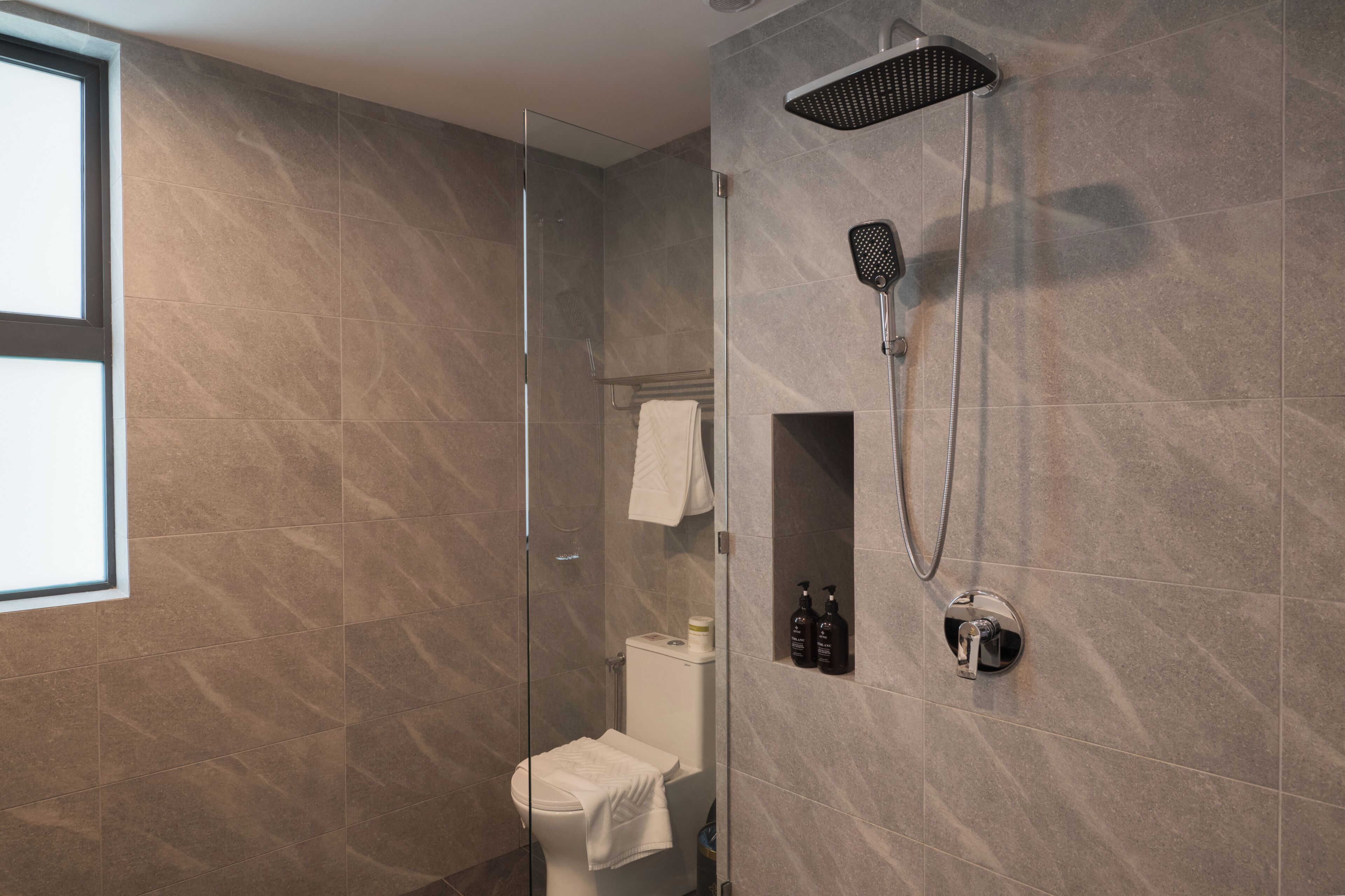 Une salle de bain moderne avec une douche à parois de verre, des toilettes et un porte-serviettes.