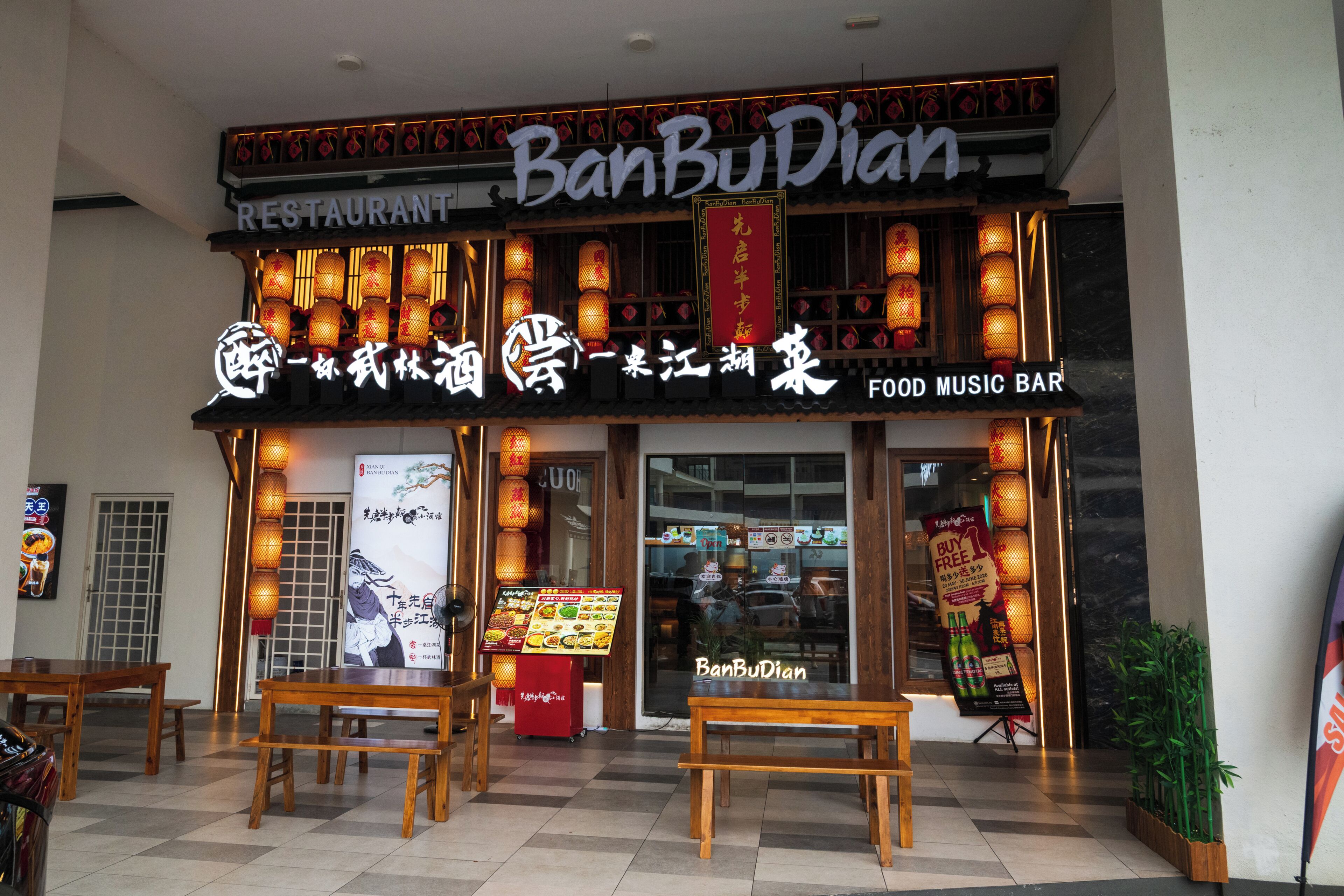 Un restaurante con un letrero tradicional chino, un bar de música y comida, y una exhibición del menú en el exterior.