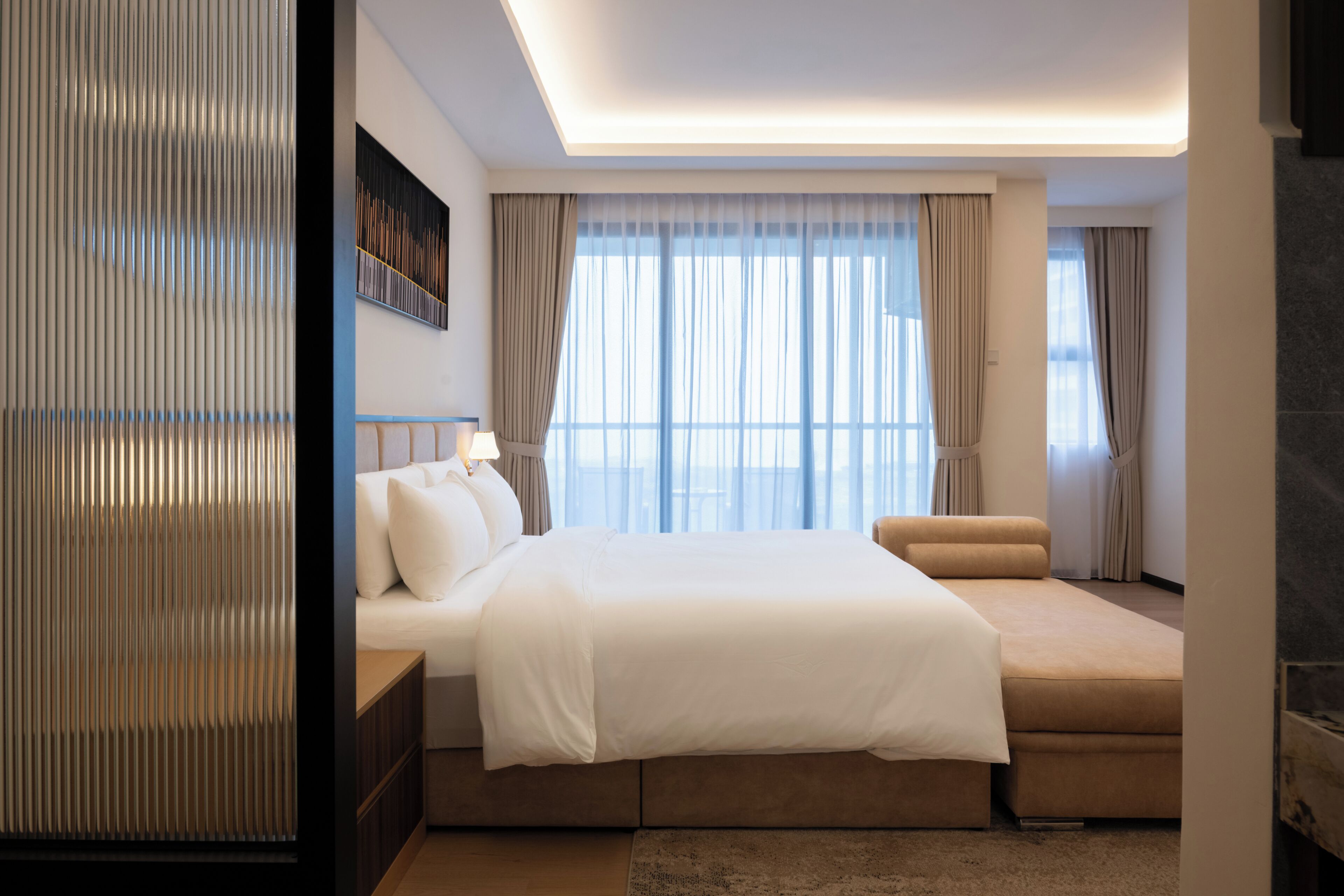 Une chambre d’hôtel moderne avec un grand lit, un canapé, une vue sur la ville et une cheminée.