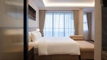 Une chambre d’hôtel moderne avec un grand lit, un canapé, une vue sur la ville et une cheminée.
