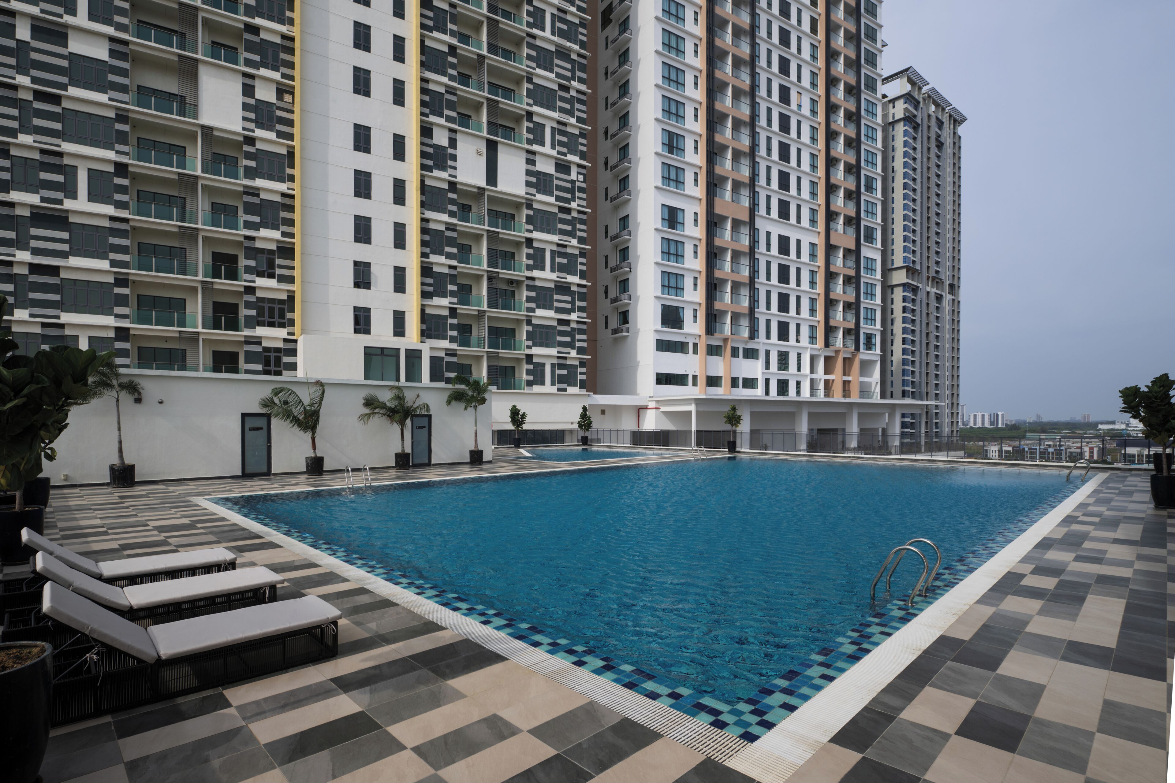 Ein Pool mit Liegestühlen und einem Hochhaus im Hintergrund.