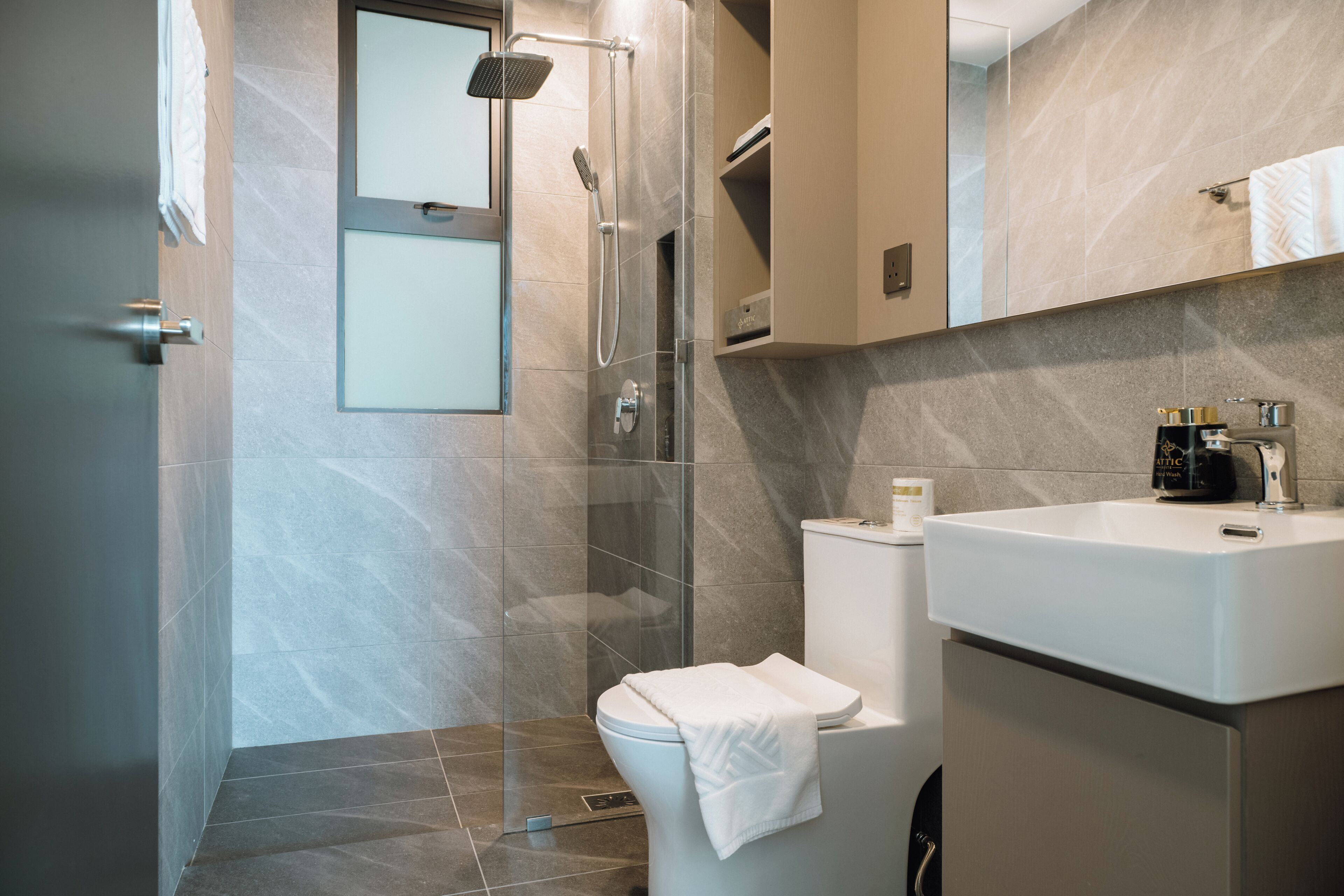 A modern bathroom with a shower, toilet, and sink.