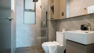 A modern bathroom with a shower, toilet, and sink.