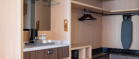 A modern bathroom with a coffee machine, mini bar, and a large mirror.