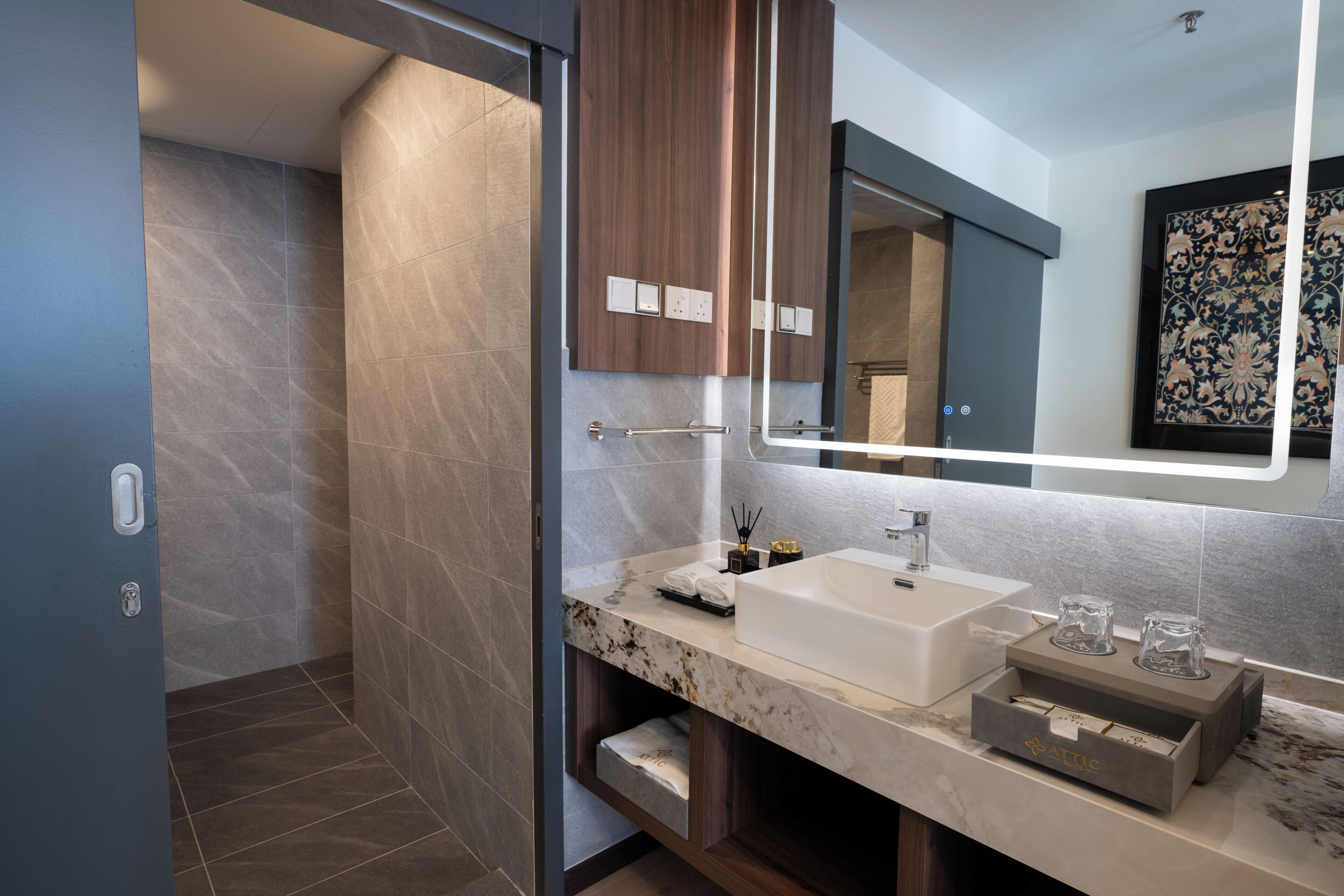 Une salle de bain moderne avec un grand miroir, un lavabo blanc et un plan de toilette en marbre.