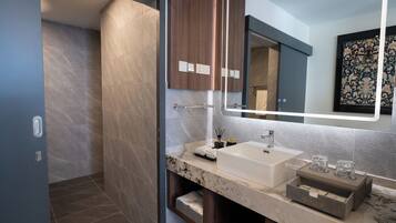 Une salle de bain moderne avec un grand miroir, un lavabo blanc et un plan de toilette en marbre.