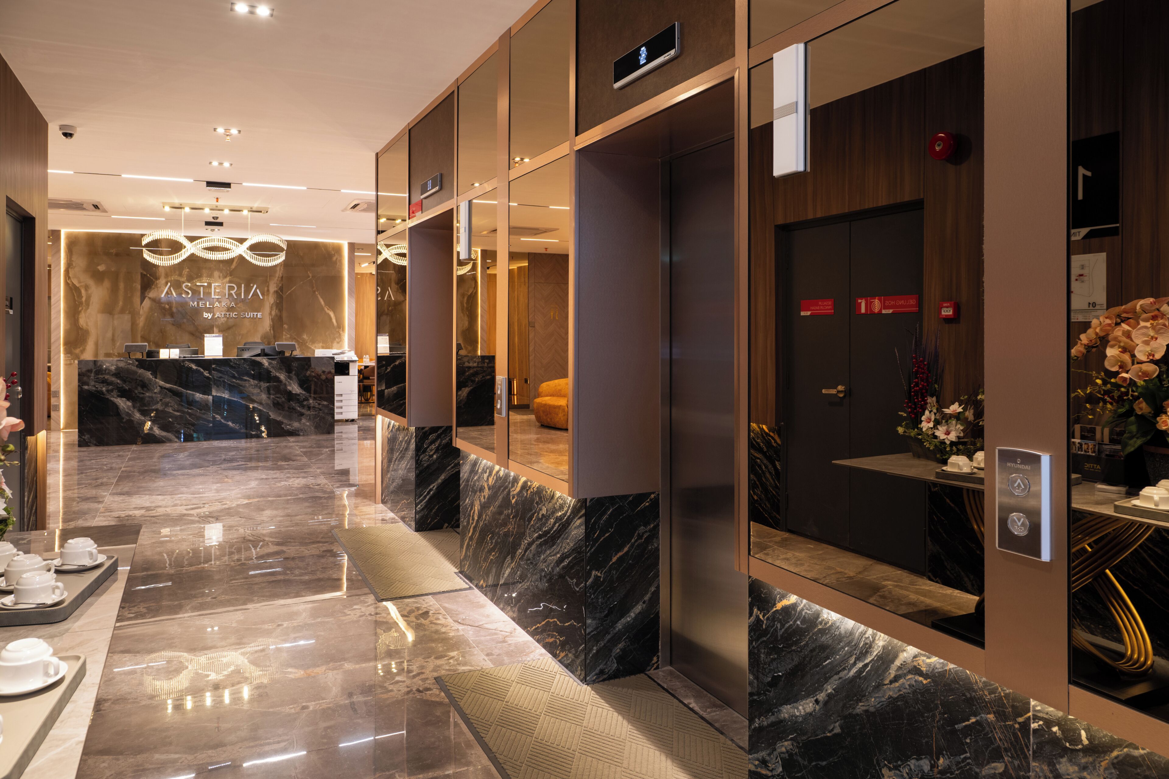 A hotel lobby with a reception desk, marble flooring, and modern decor.