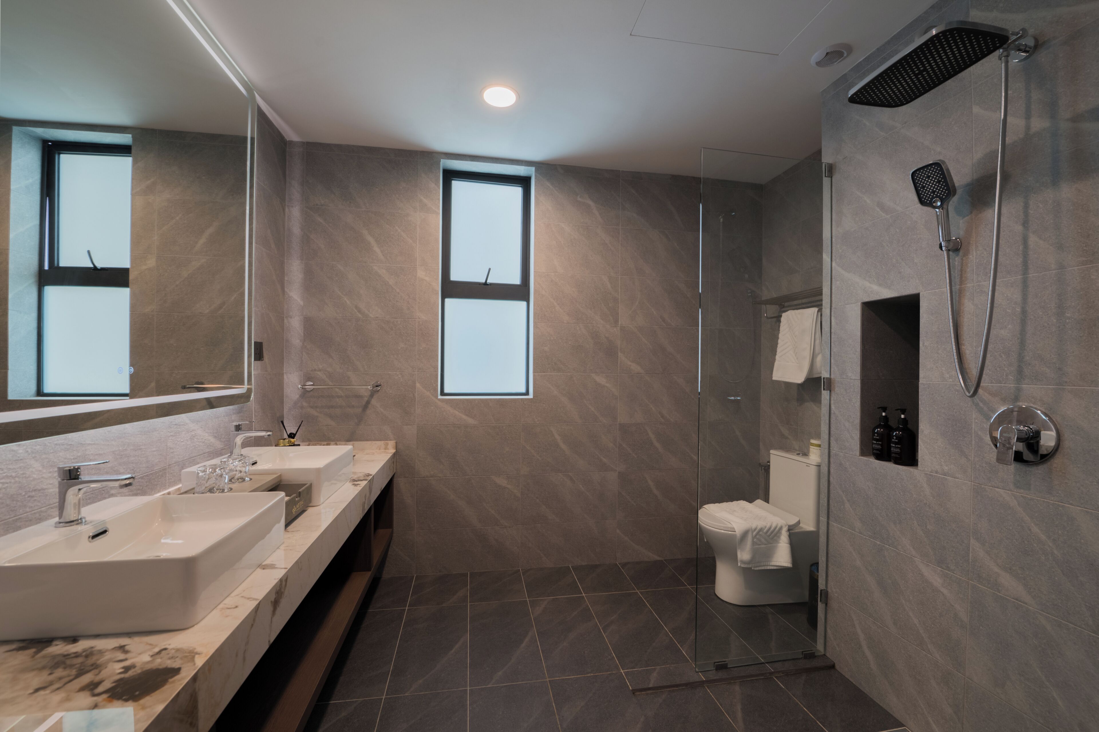 Un baño moderno con dos lavamanos, ducha e inodoro.