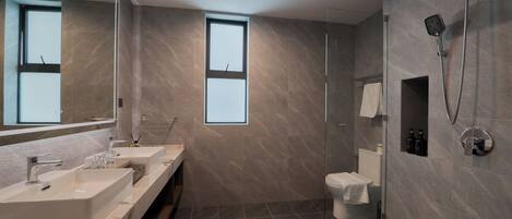 Un baño moderno con dos lavamanos, ducha e inodoro.