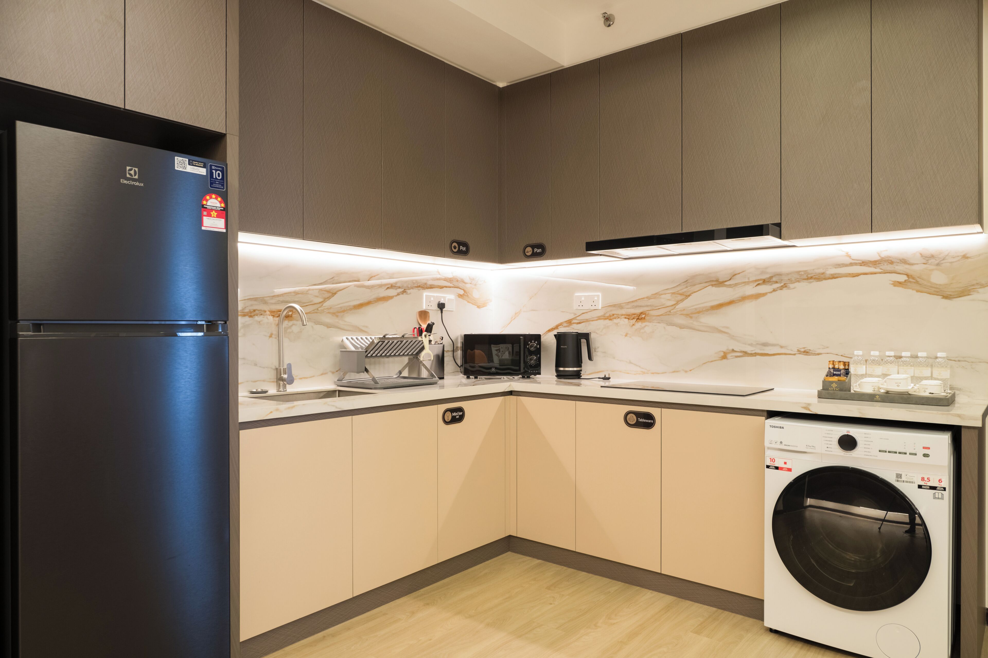 Eine moderne Küche mit Einbauwaschmaschine, Kühlschrank und Mikrowelle.