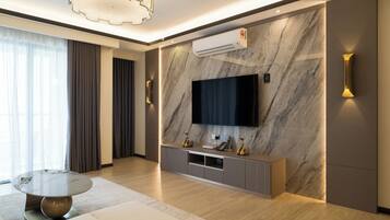A modern living room with a flat-screen TV mounted on a marble wall, a round coffee table, and a sofa.