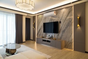 A modern living room with a flat-screen TV mounted on a marble wall, a round coffee table, and a sofa.