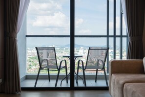 Una habitación con un ventanal grande, dos sillas, una mesita y un sofá.