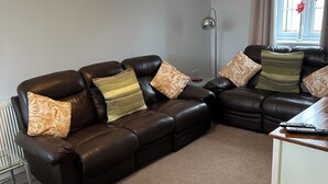 Ein Wohnzimmer mit einem braunen Ledersofa, einem Glastisch und einer Lampe.