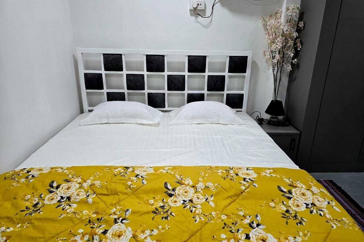 A bed with a white headboard and a yellow floral bedspread.