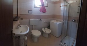 Ein Badezimmer mit Waschbecken, Toilette, Bidet und einer Dusche in Glaswand.