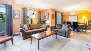 Uma sala de estar com dois sofás, uma mesa de centro e um espaço de jantar com mesa e cadeiras.