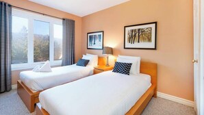 Quarto de hotel com duas camas, uma janela grande e obras de arte nas paredes.