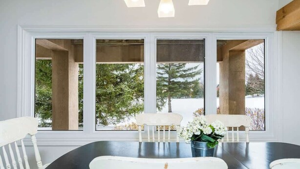 A dining area with a large window, white chairs, and a table with a vase of flowers. - The Mountain House - Walk to the Village! (The Blue Mountains)