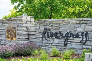 A stone wall with the name 'Rivergrass' and a decorative metal sign. - The Blue  - Walk to the Village, Shuttle & Pool (The Blue Mountains)