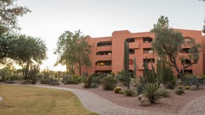 Un edificio de varios pisos con techo plano y un camino de ladrillo que lleva a la entrada.
