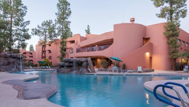 Un resort con piscina, mobiliario exterior y un edificio de diseño arquitectónico distintivo.