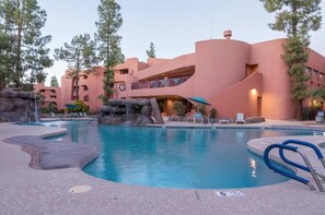 Un resort con piscina, mobiliario exterior y un edificio de diseño arquitectónico distintivo.