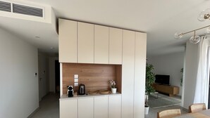 A modern kitchen with a built-in island, a dining area with a wooden table, and a living room with a TV. - Voiles Blanches 133 by Avecoeur (Vallauris)