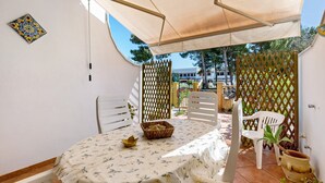 Une terrasse avec une table, des chaises, un élément décoratif suspendu et une plante en pot.