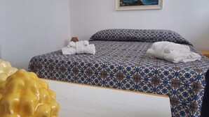 A hotel room with a bed, pillows, and a painting on the wall. - Casa Concettina: Mountain View, Balcony & Air Conditioning (San Vito Lo Capo)