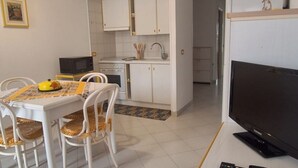 A compact living space with a dining area, kitchenette, and a television. - Casa Concettina: Mountain View, Balcony & Air Conditioning (San Vito Lo Capo)