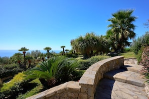 A stone staircase leading to a lush garden with various plants and a view of the sea. - Villa Hermes - luxury villa with pool and sea view (Sant'Agata sui Due Golfi)