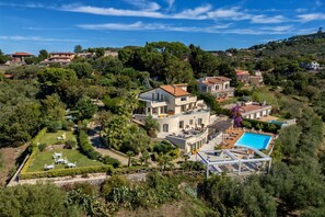 Uma grande villa com piscina, vários quartos para hóspedes e um jardim bem cuidado.