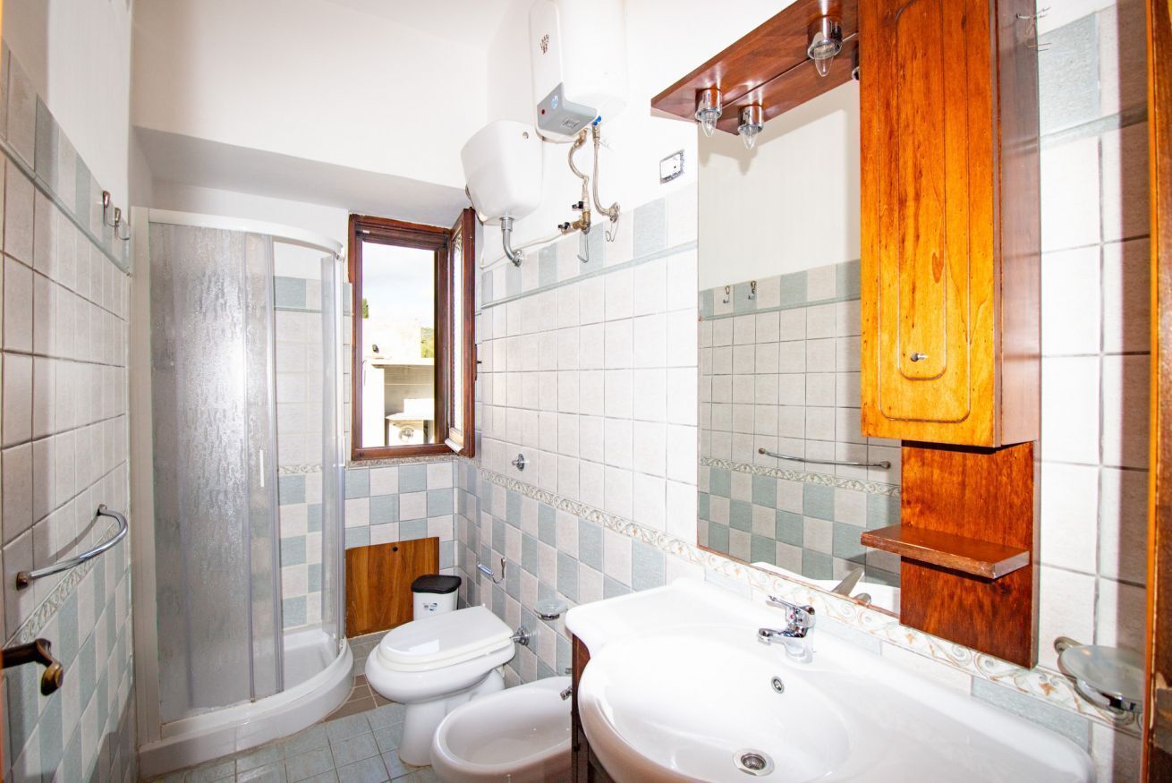 Un bagno con doccia, due servizi igienici, un lavandino e mobiletti in legno.