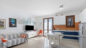 A modern living room with a sofa, TV, and dining area. - Holiday Home 'Berta' with Sea View, Private Terrace and Air Conditioning (San Vito Lo Capo)