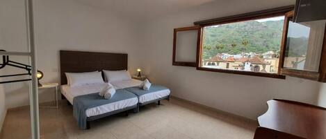 Un dormitorio con cama, mesitas de noche, una ventana con vistas y un espejo.
