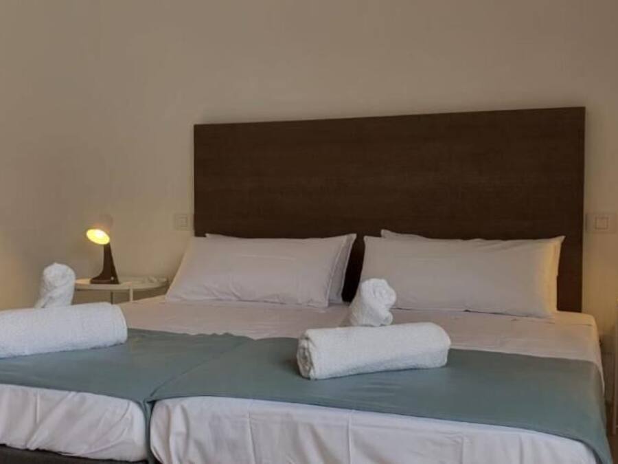 A double bed with white linens, two bedside tables with lamps, and a dark headboard.