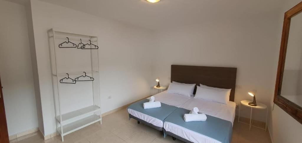 Habitación doble con dos camas, un armario con perchas, lámparas de noche y un espejo.