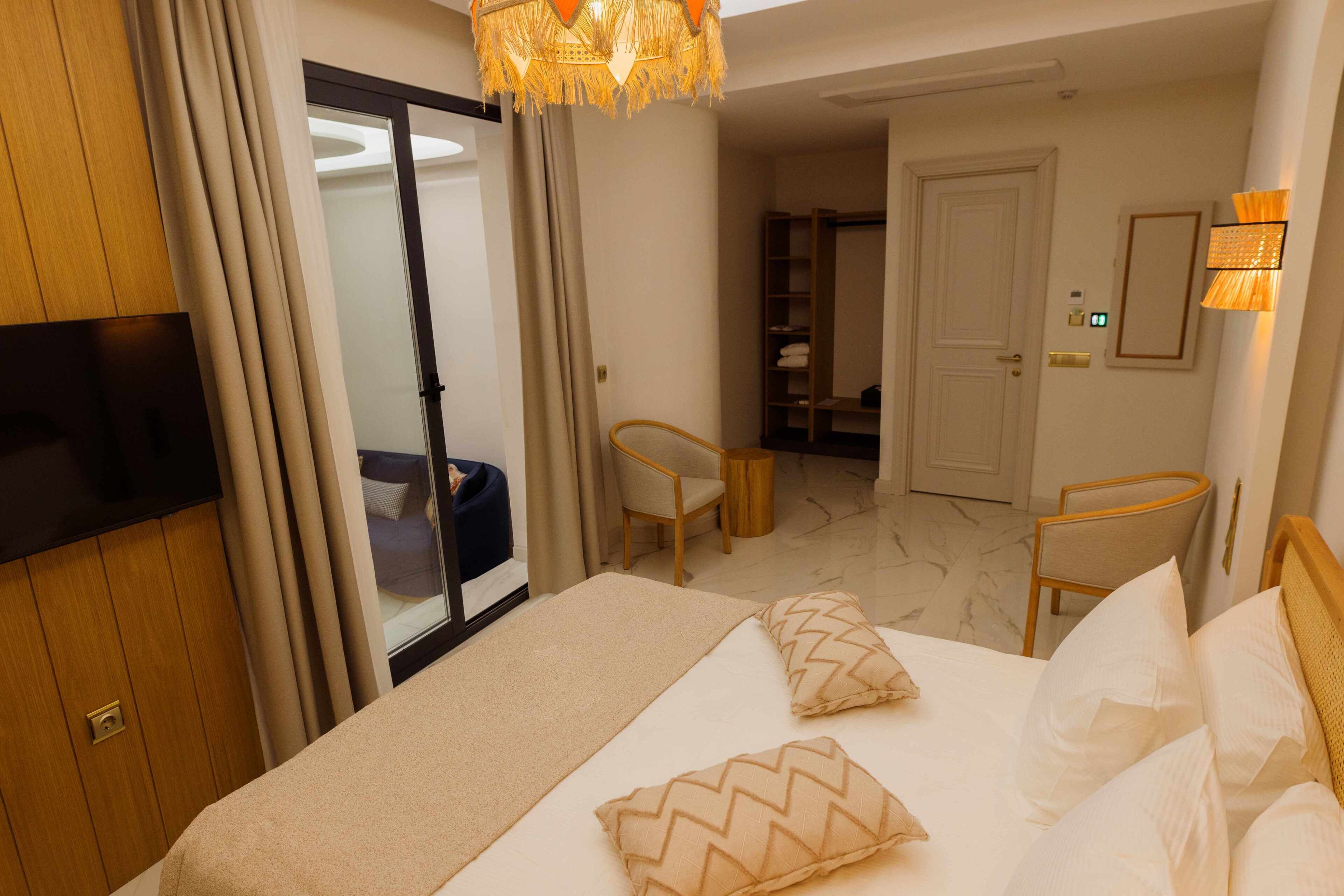 A hotel room with a bed, a television, a desk, a chair, and a wardrobe.