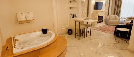 A luxurious bathroom with a freestanding bathtub, a vanity with a mirror, and a seating area with a sofa and armchairs.