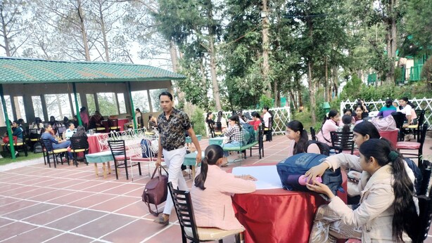 A covered outdoor seating area with tables and chairs, surrounded by trees. - Potter's Hill (Shimla)