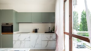 Eine moderne Küche mit Backofen, einer Marmorarbeitsplatte und Blick durch ein großes Fenster.
