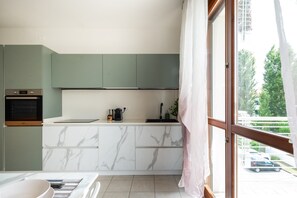 Eine moderne Küche mit Backofen, einer Marmorarbeitsplatte und Blick durch ein großes Fenster.
